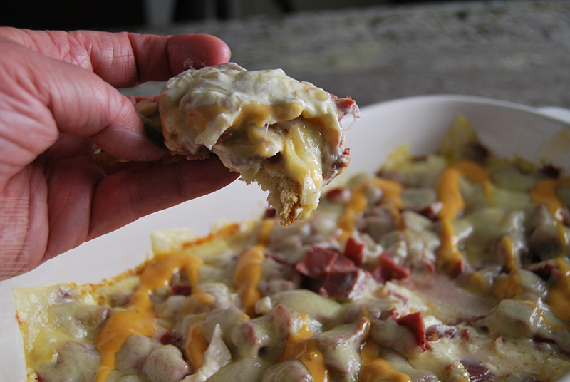 Reuben dip being served on rye bread with melty pulled swiss cheese