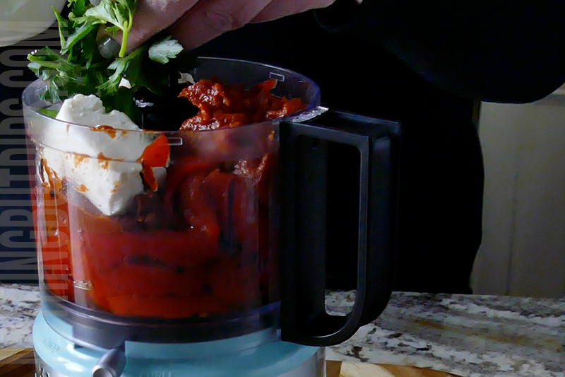 adding ingredients to the mini food processor to make roasted red pepper dip puree