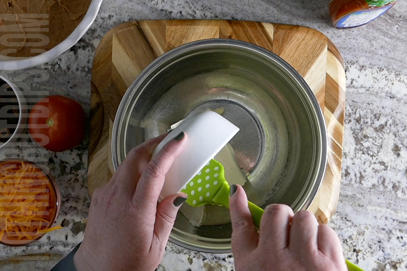 adding ingredients to the bowl for layered taco dip base