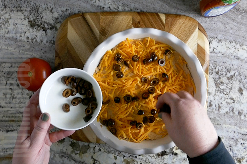 garnishing layered taco dip with black olives