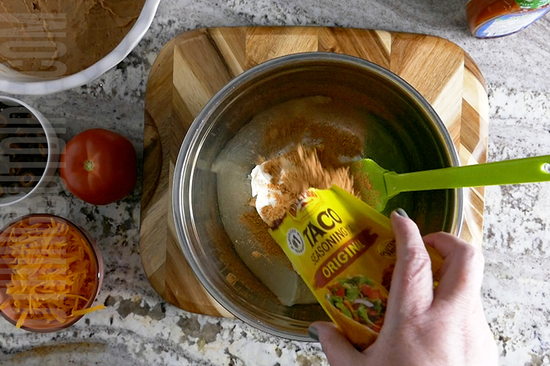 adding taco seasoning to cream cheese and sour cream