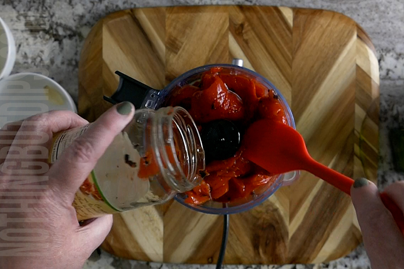 pouring the roasted red peppers into the mini food processor