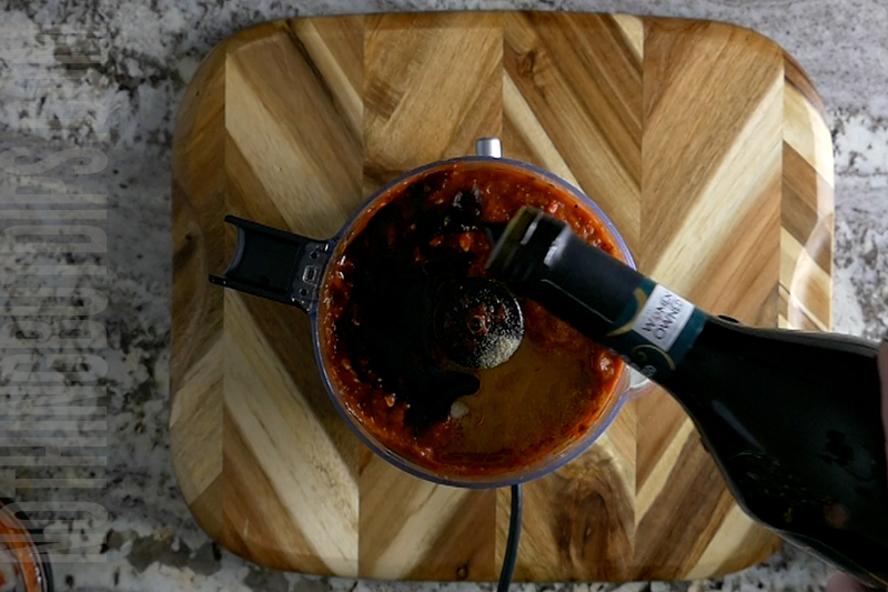 adding balsamic vinegar to the roasted red pepper dip puree