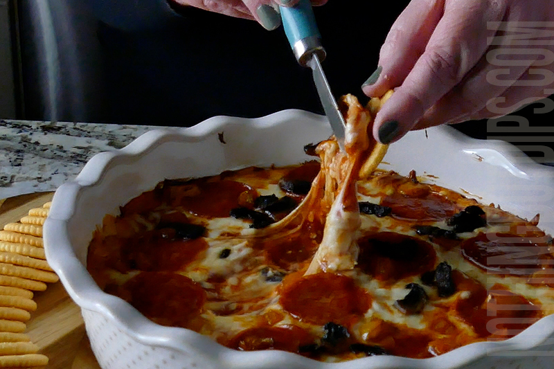 Cheesy pepperoni pizza dip served with a cracker