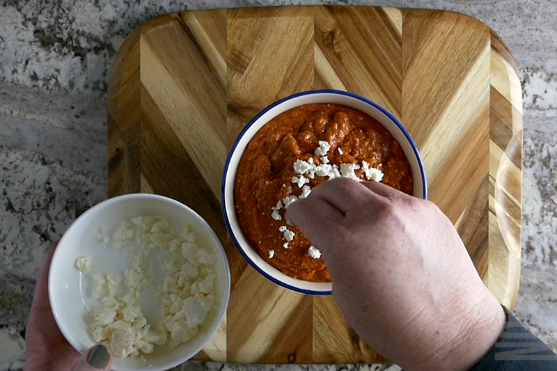 garnishing the roasted red pepper dip puree with feta cheese