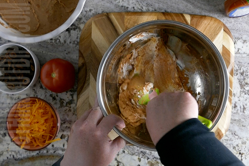 mixing cream cheese, sour cream and taco seasoning for layered taco dip