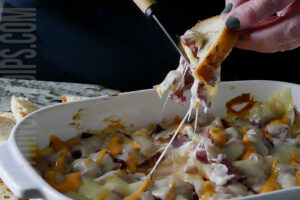 Reuben dip being served on rye bread with melty pulled swiss cheese