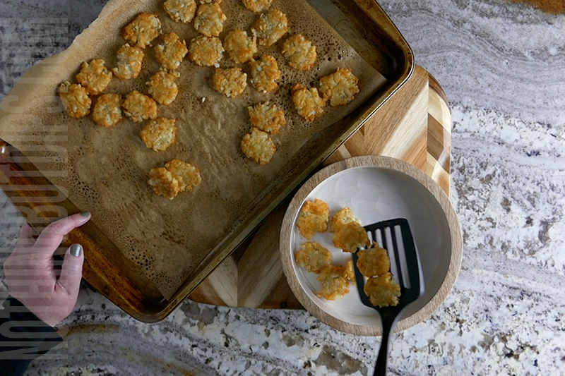 transferring the tater tot chips from the baking sheet to a bowl