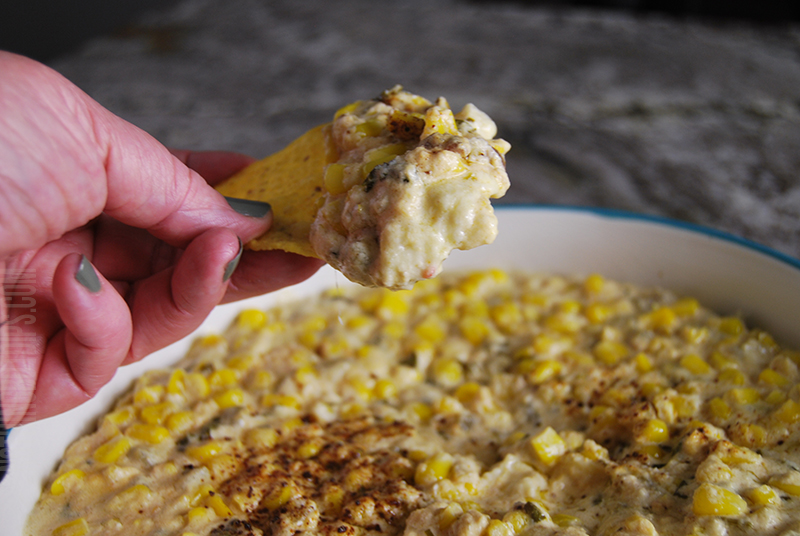 easy Mexican corn crockpot dip being served on a tortilla chip