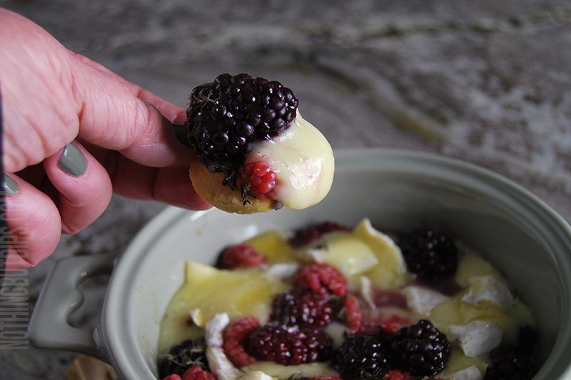 Brie with Berries and herbs being served on crusty bread