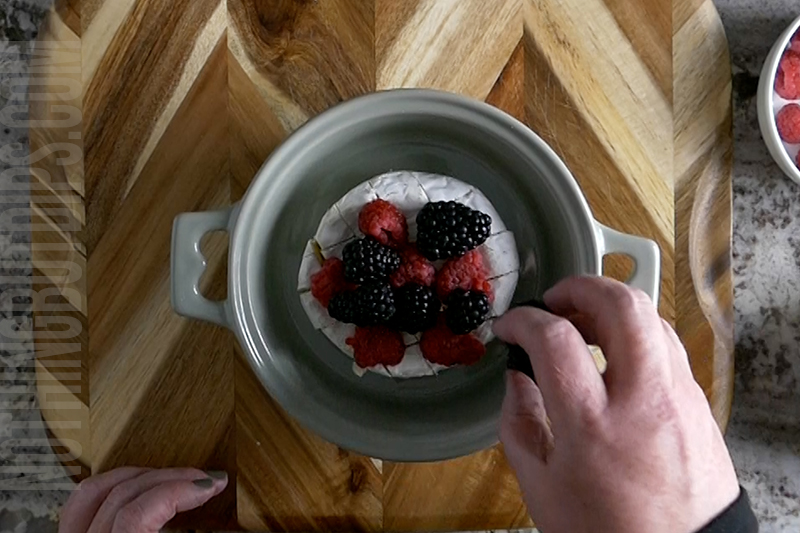 adding berries to the scored wheel of brie