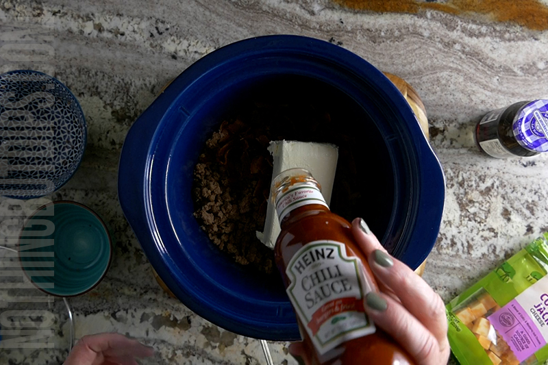 chili sauce being added to sweet and sour beef and cheese dip (aka put a ring on it cheese dip)