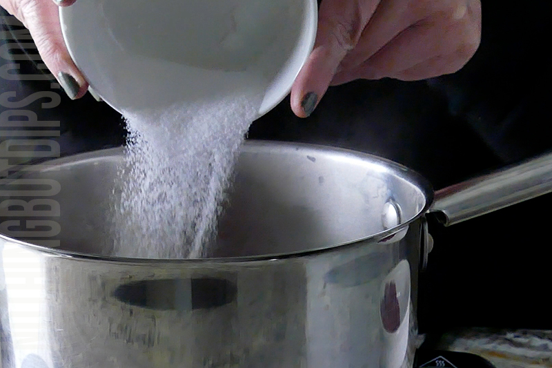 adding sugar to a pot to make a compote for the top of the strawberry basil cheesecake dip