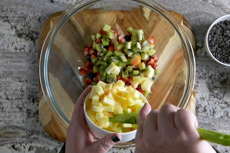 adding apple to a bowl to make fruit salsa 
