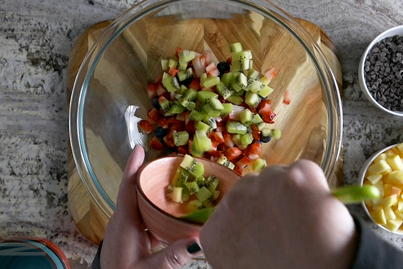 adding kiwi to a bowl to make fruit salsa