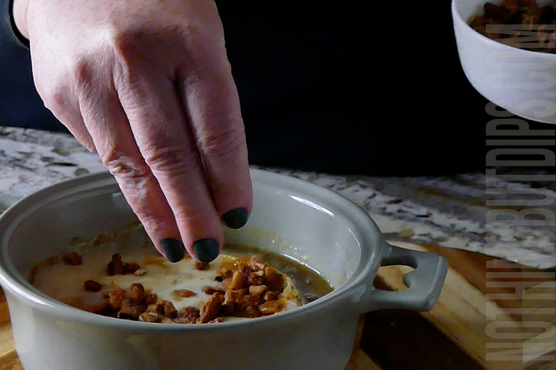 topping the melted brie with fig jam with honey roasted pecans