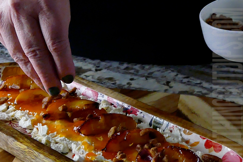 adding honey roasted pecans to the top of the Boursin and jam dip appetizer