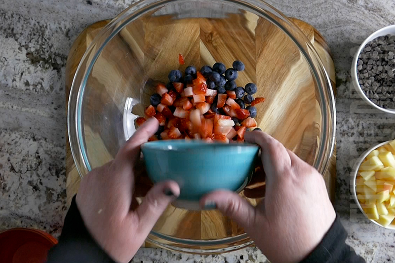 adding strawberries to a bowl to make fruit salsa