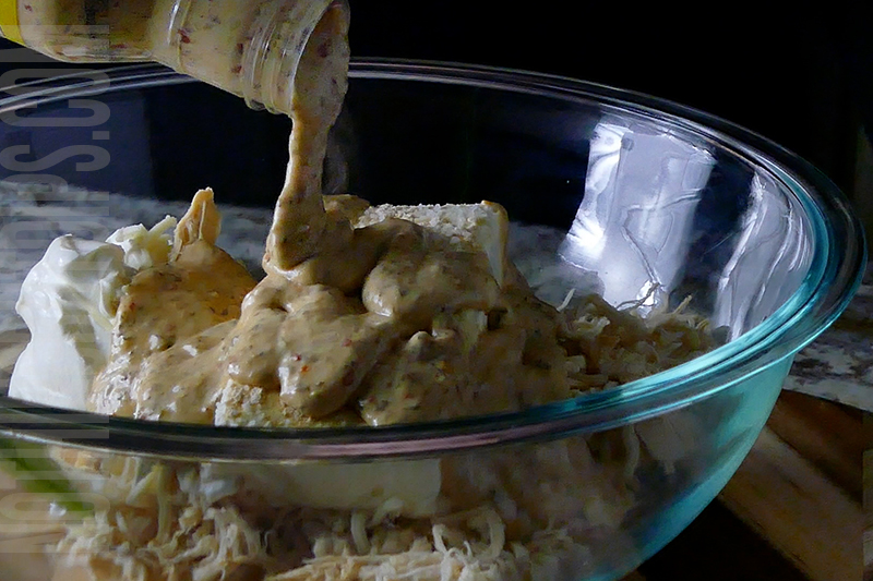 adding parmesan garlic wing sauce to the mixing bowl to make parmesan garlic wing dip
