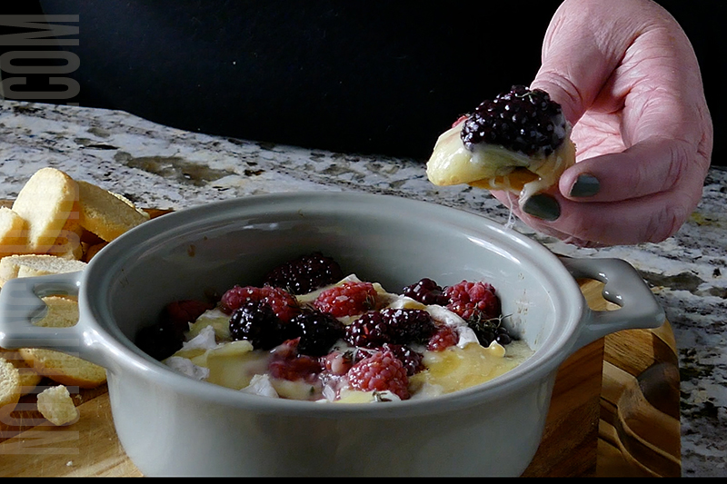 Brie with Berries and herbs being served on crusty bread