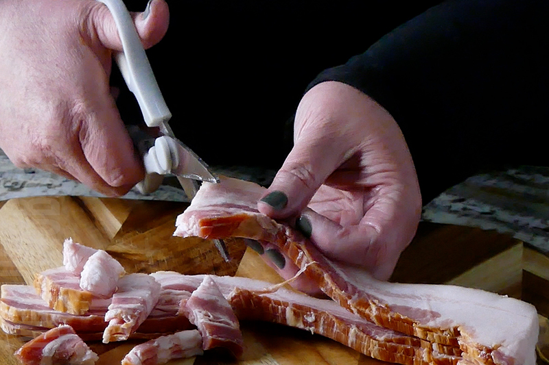 chopping bacon with kitchen scissors