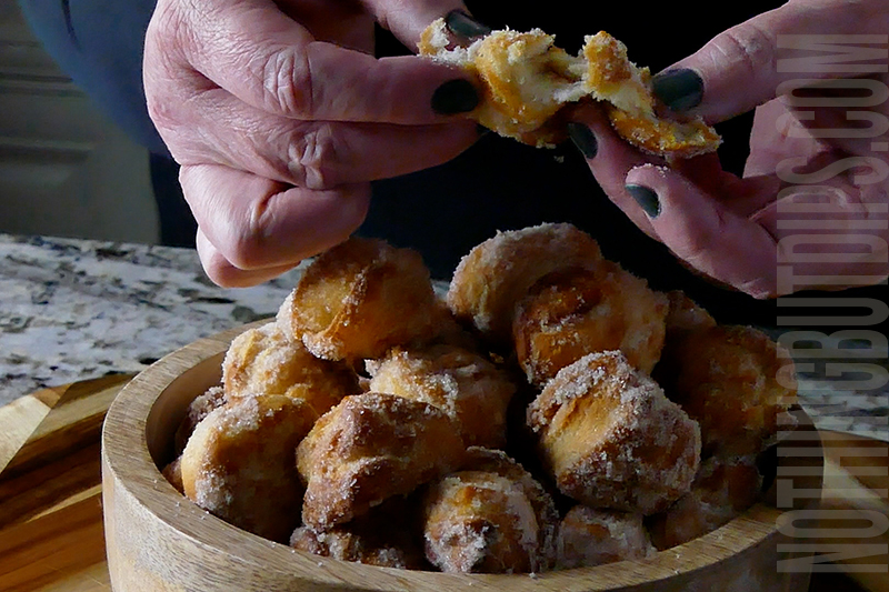 easy air fryer donuts being served in a bowl and a donut hole being broken in half