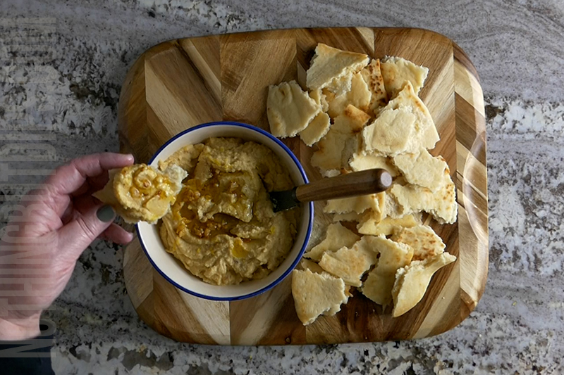 lemon garlic hummus served on a wooden board with warmed pita bread
