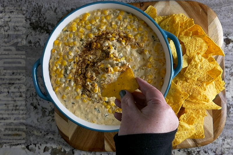 easy Mexican corn crockpot dip being served on a tortilla chip