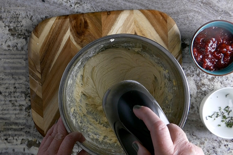 using a hand mixer to mix and make the creamy base for strawberry basil cheesecake dip