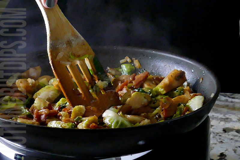 stirring the brussels sprouts, bacon, onion and balsamic vinegar as it sautes in the pan