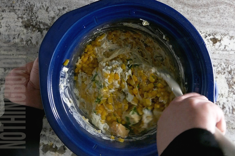 stirring the Mexican corn dip in the crockpot once cheese has started to melt