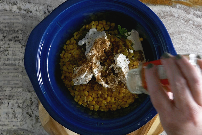 adding chili lime seasoning to the Mexican corn crockpot dip