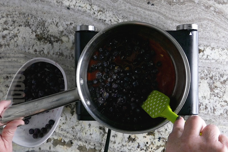 cooking down frozen blueberries and sugar to create a blueberry compote
