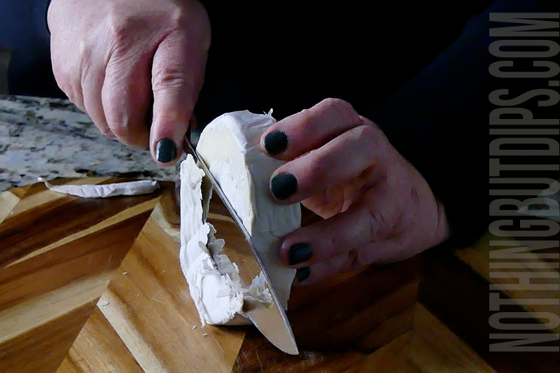 cutting the wax top off the brie cheese