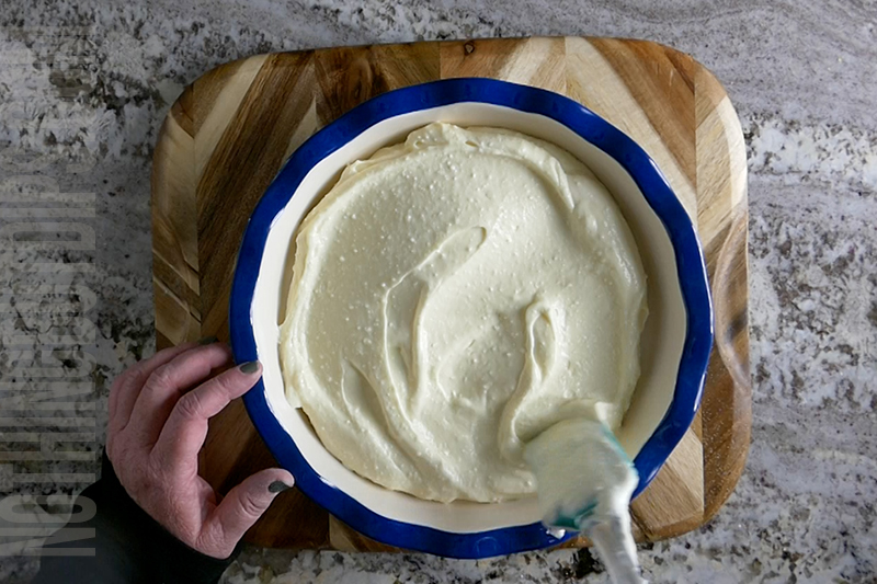 spreading out the creamy base for the key lime pie dip in a decorative pie dish