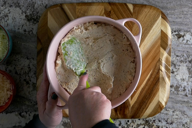 spreading the chicken mixture in the baking dish as part of the preparation for parmesan garlic wing dip