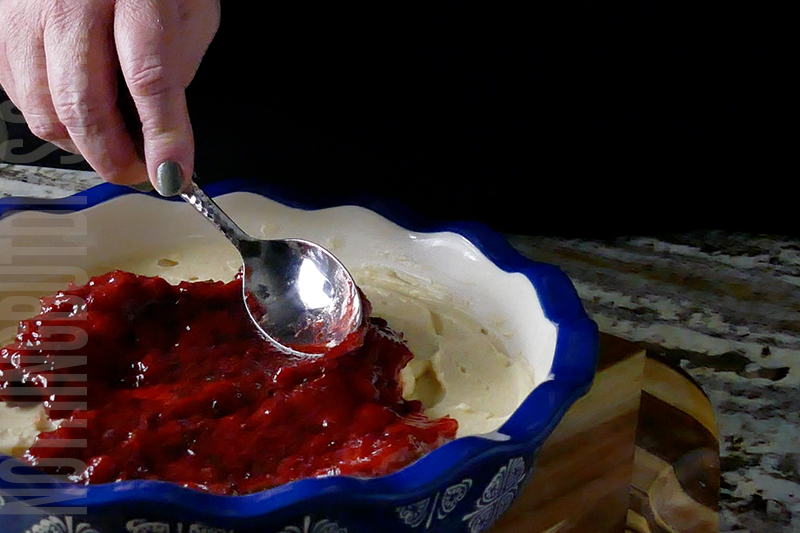 spreading the strawberry compote on top of the creamy base to create the strawberry basil cheesecake dip