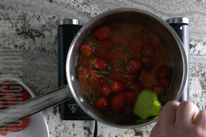 simmering strawberries and sugar over low heat to make a compote for the top of the strawberry basil cheesecake dip