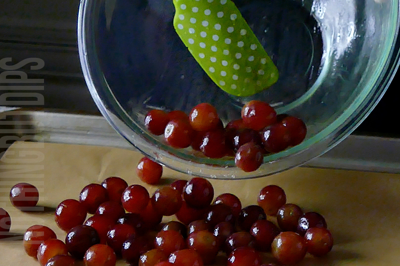 placing grapes coated in olive oil on a baking sheet