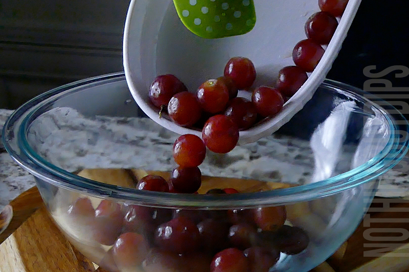 adding grapes to a mixing bowl