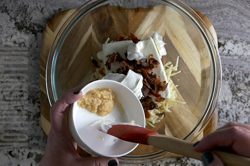adding horse radish to a bowl to make a classic cheese ball