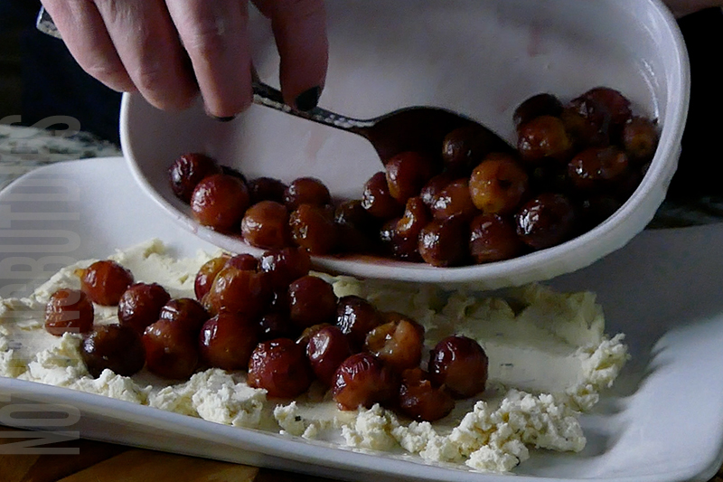 laying roasted grapes on top of Boursin cheese to make a delicious appetizer