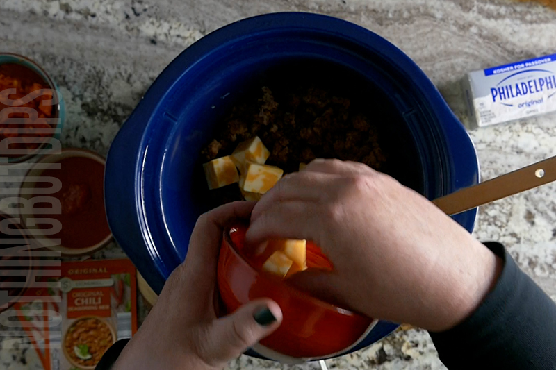 adding cubed colby jack cheese to the crockpot to make chili cheese dip
