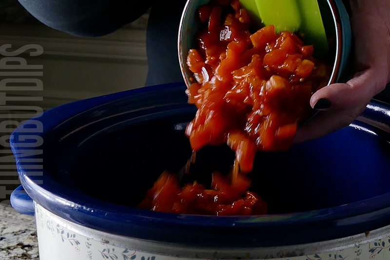 adding diced tomatoes to the crockpot to make chili cheese dip