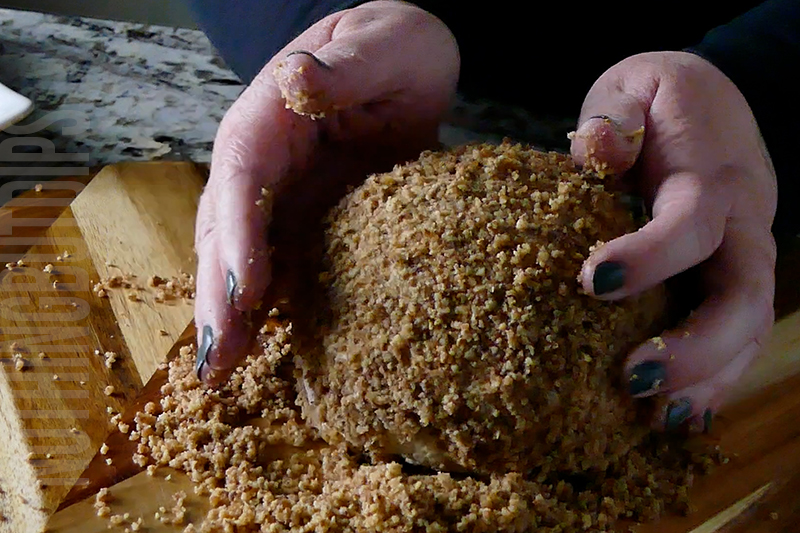 covering the cheese ball in crushed honey roasted pecans
