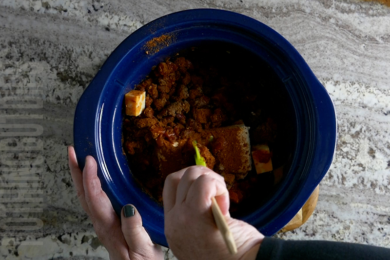 mixing the chili cheese dip as it cooks in the crockpot