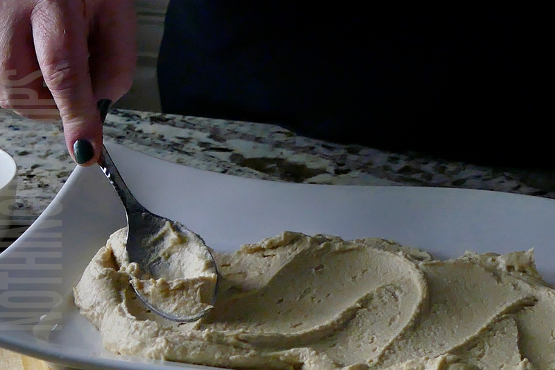 spreading hummus onto a serving dish