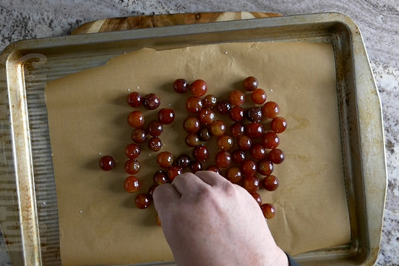 sprinkling olive oil coated grapes with salt