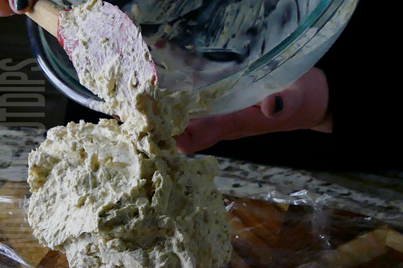 transferring the ingredients from a bowl to cling wrap to make a classic cheese ball