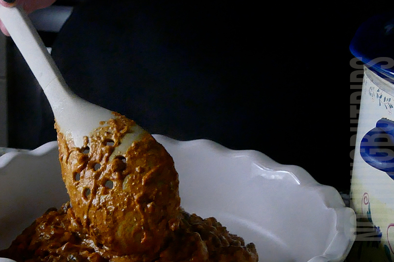 transferring the chili cheese dip from the crockpot to a serving dish 